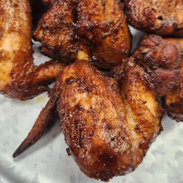 Close-up of several glistening, dark brown BBQ chicken wings from Fat Man's BBQ.