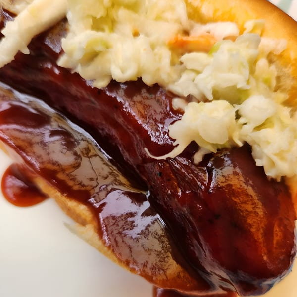 Close-up of a Fat Man's BBQ hot dog with coleslaw and barbecue sauce.
