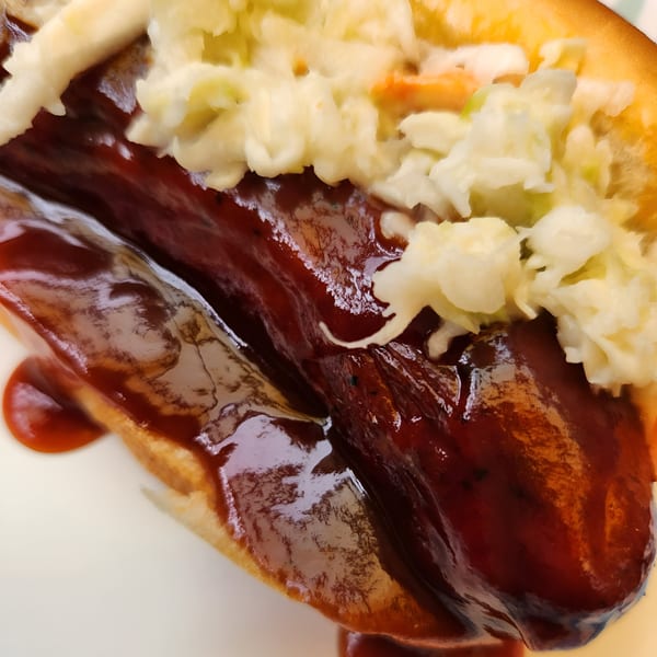Close-up of a Fat Man's BBQ hot dog with coleslaw and barbecue sauce.
